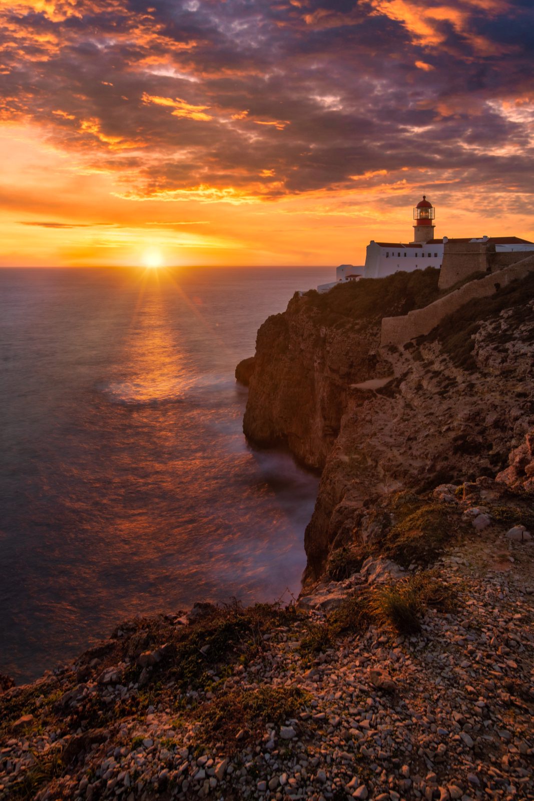 Küstenleuchtturm auf einer Klippe bei Sonnenuntergang über dem Meer.